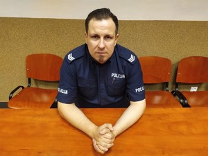 zdjęcie przedstawia policjanta siedzącego przy stole
