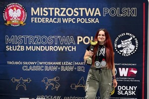 zdjęcie przedstawia policjantkę w stroju sportowym z pucharem i medalami na szyi