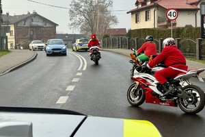 zdjęcie przedstawia policjantów zabezpieczających przejazd motocyklistów w strojach mikołajów