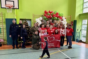 zdjęcie przedstawia policjanta niosącego paczkę dla potrzebującej rodziny