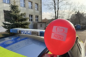 zdjęcie przedstawia policjanta niosącego paczkę dla potrzebującej rodziny