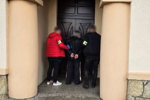 Na zdjęciu widać nieumundurowanych policjantów, którzy doprowadzają zatrzymanego