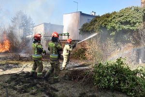 Strażacy gaszący pożar na terenie posesji