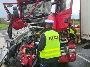 Policjant stoi obok rozbitego pojazdu ciężarowego