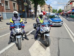 Zdjęcie przedstawia policjantów na motocyklach oraz policyjny radiowóz podczas zabezpieczenia pielgrzymki mężczyzn