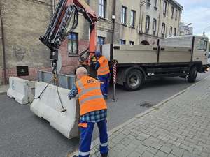 Zdjęcie pracowników zakładu gospodarki komunalnej podczas układania betonowych zapór