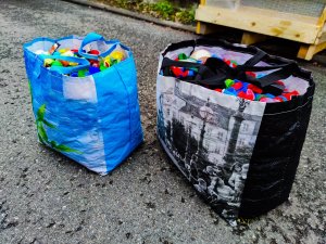 Zdjęcie kolorowe: dwie torby wypełnione plastikowymi nakrętkami