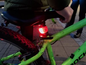 Zdjęcie kolorowe: czerwona lampa rowerowa przypięta do rury roweru