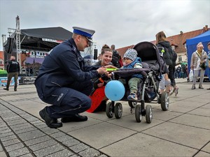 Zdjęcie kolorowe: umundurowany policjant przy wózku dziecięcym wraz z kobietą