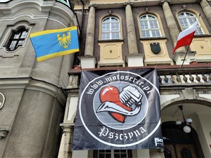 Zdjęcie kolorowe: baner promujący wydarzenie, a obok niego flaga polski i śląska