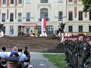 Zdjęcie kolorowe: na pierwszym planie widoczny zamek pszczyński przed którym odbywa się msza polowa. Z prawej strony widoczni mundurowi.