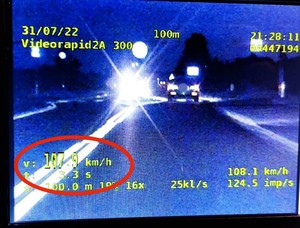 Zdjęcie kolorowe: zdjęcie wideorejestratora, widoczny samochód oraz zaznaczony pomiar prędkości.