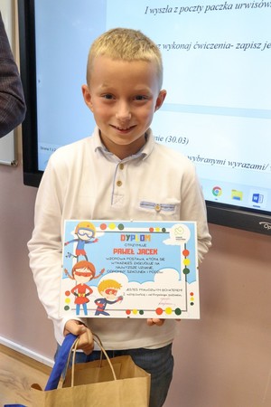 Zdjęcie kolorowe chłopca przedstawia chłopca z dyplomem.