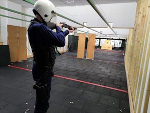Zdjęcie przedstawia umundurowanego policjanta podczas strzelań ćwiczebnych z broni długiej.