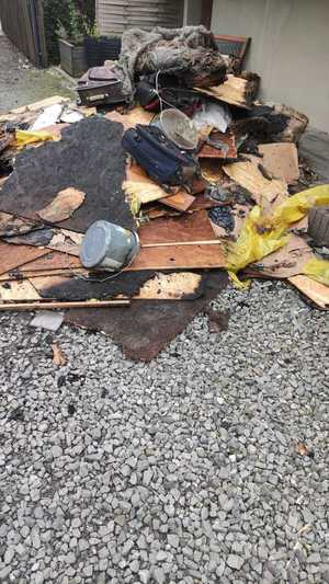 Zdjęcie przedstawia wyrzucone rzeczy z płonącego budynku.