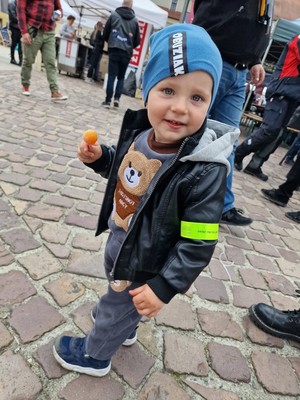 Zdjęcie przedstawia: małego chłopca z opaską odblaskową na rączce.