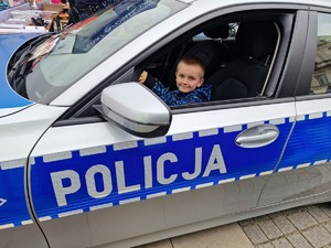 Zdjęcie przedstawia: chłopca, który siedzi w policyjnym radiowozie.