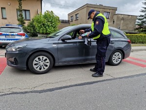 Zdjęcie przedstawia: funkcjonariusz Straży Ochrony Kolei podczas wręczania gadżetów kierowcy zatrzymanego pojazdu.