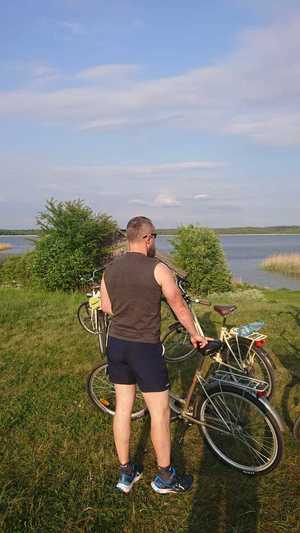 Zdjęcie przedstawia: mężczyznę obok roweru.