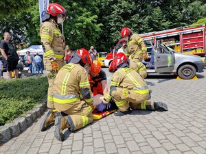 Zdjęcie przedstawia: ratownika medycznego oraz strażaków którzy udzielają pierwszej pomocy