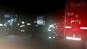 Zdjęcie w nocy. Widoczni strażacy, policjanci, wozy służb ratunkowych.