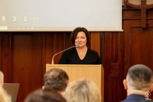 Zdjęcie przedstawia: kobietę na mównicy podczas przemówienia.