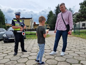 Zdjęcie przedstawia: dziecko, policjanta i mężczyznę podczas rozmowy.