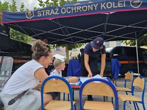 Zdjęcie przedstawia uczestników wydarzenia przy prezentowanych namiotach służb mundurowych.