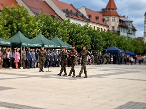 Zdjęcie przedstawia maszerujących żołnierzy z flagą.