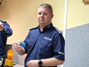 Zdjęcie przedstawia: 
Umundurowanego policjanta trzymającego w ręku brelok wozu policyjnego.