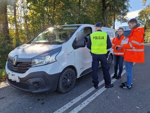 Zdjęcie przedstawia: 
Policjanta i dwóch przedstawicieli Kolei Śląskich rozmawiających z kierowcą dużego samochodu.