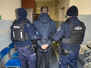 Zdjęcie przedstawia: dwóch policjantów z zatrzymanym mężczyzną.