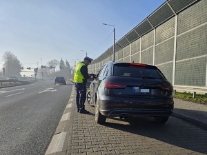 Zdjęcie przedstawia: policjanta przy samochodzie podczas kontroli drogowej.