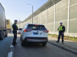 Zdjęcie przedstawia: policjantów obok kontrolowanego samochodu.