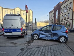 Zdjęcie przedstawia: uszkodzony samochód osobowy w wyniku kolizji, obok zaparkowany radiowóz.