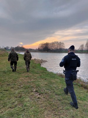 Zdjęcie przedstawia: dwóch funkcjonariuszy nadleśnictwa wraz z umundurowanym policjantem.