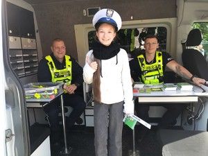 Zdjęcie przedstawia: dwóch policjantów oraz dziewczynkę z czapką policyjną na głowie.