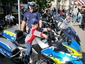 Zdjęcie przedstawia: chłopca siedzącego na motocyklu policyjnym.