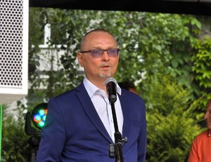 Zdjęcie przedstawia: mężczyznę mówiącego do mikrofonu