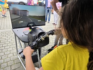 Zdjęcie przedstawia: dziecko, które jeździ na symulatorze jazdy motocyklem