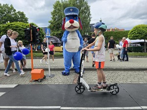 Zdjęcie przedstawia: dzieci w miasteczku rowerowym i maskotkę policyjną