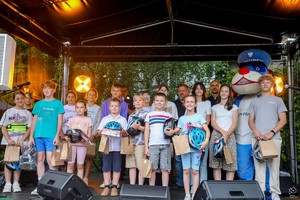 Zdjęcie przedstawia: dzieci z maskotką na scenie