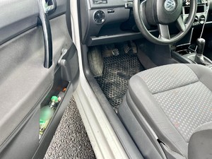 Zdjęcie przedstawia: otwarte drzwi samochodu po stronie kierowcy i butelki z alkoholem.