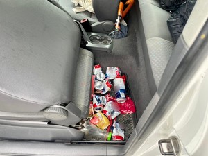 Zdjęcie przedstawia: tylną wycieraczkę w samochodzie i leżące na niej puszki po piwie.