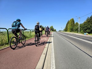 Zdjęcie przedstawia: ludzi jadących na rowerach po ścieżce rowerowej.