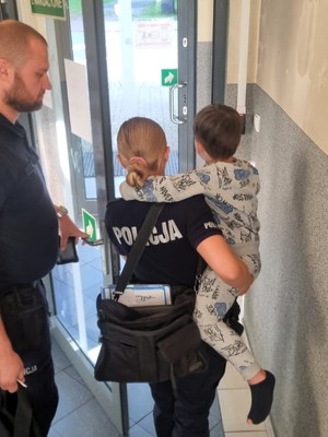 Zdjęcie przedstawia: umundurowaną policjantkę, która trzyma małego chłopca na rękach.