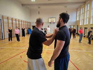 Zdjęcie przedstawia: policjanta trzymającego uczestnika za koszulkę.