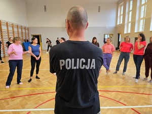 Zdjęcie przedstawia: policjanta i rozmawiających uczestników.