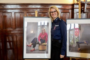 zdjęcie przedstawia: uśmiechniętą policjantkę wraz ze swoim zdjęciem z wystawy.