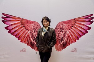 zdjęcie przedstawia: kobietę wraz z namalowanymi różowymi skrzydłami.